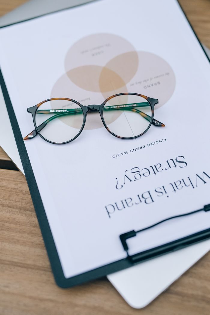 Close-up of eyeglasses resting on a clipboard with brand strategy text.