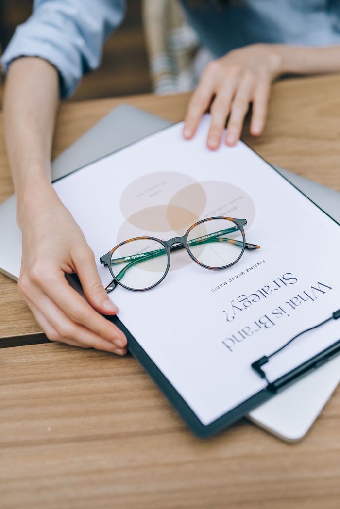 Close-up of eyeglasses on clipboard with brand strategy document, emphasizing business planning and analysis.